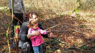 <p>Die dreijährige Alexa übt sich mit der Hilfe von Mama Bianca Mayer im Führen eines Feldbogens, während Andrea Brown (Mitte) bereits den ersten Schaumstoff-Hasen getroffen hat und ihren Pfeil herauszieht. Rainer Winkler, Vorsitzender des Feldbogenclubs, zeigt, wie man richtig zielt.</p>
