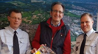Polizeirat Elmar Hörscher (r.), Leiter des Reviers in Neckarau und Polizeihauptkommissar Alfred Bauer (l.), Leiter des Postens Brühl, wollen weiter präventiv an einem niedrigen Stand der Kriminalität in der Hufeisengemeinde arbeiten und übergeben ein Plakat für eine weitere Aktion an Bürgermeister Dr. Ralf Göck.