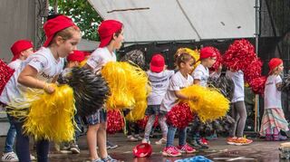 Die Mädchen und Jungen aus der Kindertagesstätte „Fohlenweide“ präsentieren mit ihren schwarzen, roten und gelben Puscheln gut gelaunt einen Weltmeister-Tanz auf der Bühne.