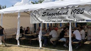 Beim Sängerbund Oberhausen sitzen die Besucher im kühlen Schatten und stärken sich zur Mittagszeit.