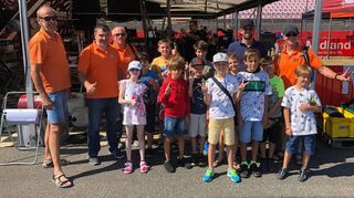 Die Ferienkinder zusammen mit Jochen Nerpel (blaues T-Shirt und Mütze) und dem Team der Verkehrswacht (orangene T-Shirts) vor der Top-Fuel-Dragster-Werkstatt des früheren FIA-Europameister Urs Erbacher.
