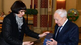 Die Vorsitzende des Kirchengemeinderats, Maria Teubner, übergibt Dr. Lothar Gaa als Präsent einen edlen Tropfen.
