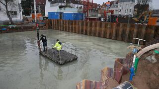 Mit dem Floß und dem Schlauch über der künftigen Bodenplatte unterwegs: Bahn für Bahn wird die 75 Zentimeter starke Abdich-tung gegen das Grundwasser für die Tiefgarage aus der Betonpumpe aufgebracht. Kurz nach 6 Uhr ging’s los.