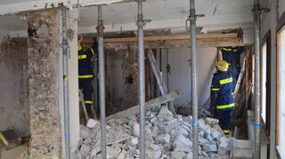 Der Bauschutt in dem Haus erschwert die Arbeiten des Technischen Hilfswerks. Die Helfer sichern die Decke mit Stützen ab, die im Vordergrund zu sehen sind.