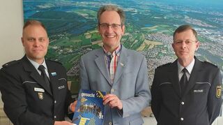 Der Leiter des Polizeireviers Mannheim-Neckarau, Elmar Hörscher (l.), überreicht im Beisein von Alfred Bauer (r.), Leiter des Polizeipostens Brühl, die neue Broschüre zur Bewerbung von Polizeinachwuchs an Bürgermeister Dr. Ralf Göck.