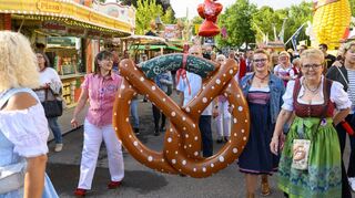Zahlreich strömen die Besucher zur Eröffnung auf den Platz. Die Schausteller bringen einen Brezelgruß mit.