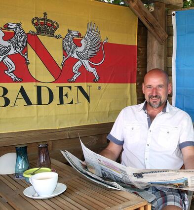 Peter Künzler an seinem Lieblingsplatz – der selbst gezimmerten „Herrenecke“ unterm Nussbaum, bei einer Tasse Kaffee und der Morgenlektüre.