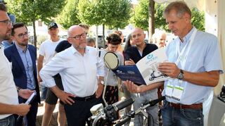 Reiner Sinemus (r.) von der Schwetzinger Firma „Green Drive“ stellt Verkehrsminister Winfried Hermann (4. v. l.) die Nito-Elektroroller vor.