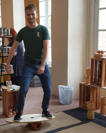 Patrick Kaiser („Rollholz“) demonstriert ein „Surfbrett“ für die Balance aus Holz.
