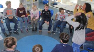 Renata Rivkin Haag (r., gelbes Shirt) leitet die Englisch-AG. Nach dem „Hello-Song“ erzählen die Kinder wie sie sich fühlen – aufgeregt, also „excited“, springen alle in die Luft.