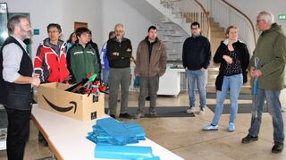 Der Organisator Bernhard Müller (l.) teilt im Gemeindezentrum die ehrenamtlichen Müllsammler in Teams ein und verteilt zahlreiche blaue Müllsäcke.