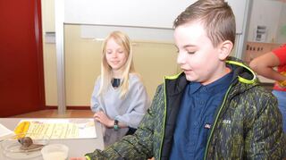 Dean traut sich die Riesenschnecke zu füttern: „Mehl, Wasser und Zucker sind in dem Brei“, erklärt er – Lilli schaut interessiert zu.