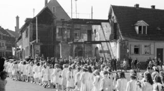 Hinter dem Kommunionszug 1952 ist zu erkennen, dass das Haus der Familie Horch immer noch nicht aufgebaut ist.