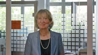 Heide-Rose Gönner, Schulleiterin der Carl-Theodor-Schule, steht im Sekretariat hinter einer Scheibe, die bei Gesprächen mit Schülern und Lehrern zum Schutz dient.