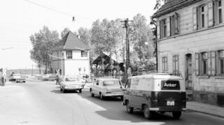 Eine Schlange von Autos bildet sich am Bahnübergang im Jahr 1965. Es konnte lange dauern, bis die Schranken wieder hoch gingen und der Zug durchgefahren war.