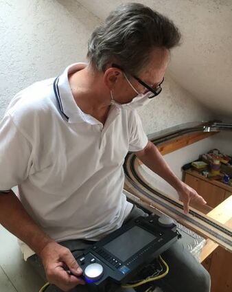 Von seinem Steuerplatz aus zeigt Heribert Kammerer auf die transparente Schutzwand, die die Züge sichert.