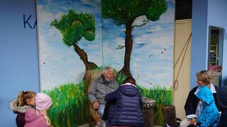 Peter Lemke sitzt in seiner Leseecke unter einem Baum und fesselt die anwesenden Kinder mit seiner Geschichte.