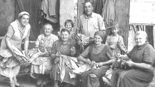 Je nach Wetterlage versammelten sich früher die Bauersfamilien mit ihren Verwandten, Bekannten oder Nachbarn in der Scheune oder im Hof, meist auf Strohballen sitzend, um Tabak einzufädeln. Auf dem Bild ist die Familie Großhans/Geiß in der Mittleren Mühlstraße 10 zu sehen.