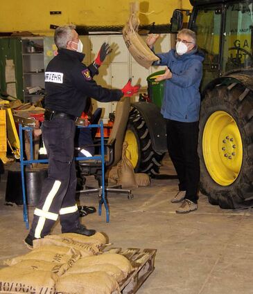 Bürgermeister Uwe Grempels (r.) wirft Feuerwehr-Kommandant Thorsten Lehrenkrauß die Sandsäcke zu.
