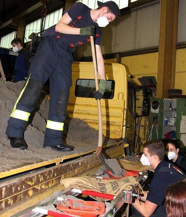 In Teamarbeit füllen die Mitglieder der Jugendfeuerwehr die Sandsäcke.