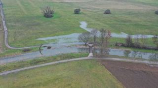 Blick aus der Luft: die Fußgängerbrücke über den Leimbach in den Schwetzinger Wiesen. Das Hochwasser drückt mehr und mehr in die Wiesen hinein.