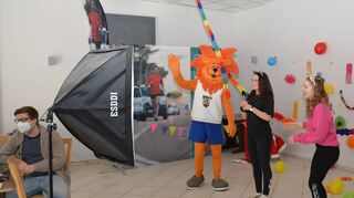 Yannick Zipf (l.) behält das Maskottchen „Schorsch“ auf dem Bildschirm im Blick, dass die Kinder daheim ihn auch gut sehen können. Der Löwe tanzt gleich die Polonaise mit den Trainerinnen.