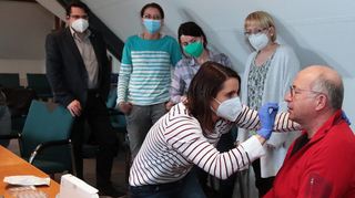 Bürgermeister Weisbrod, Melanie Endreß (Haus der kleinen Hasen), Elisa Rehberger (Schillerschule) und Eva Krause (Die kleinen Sterne) beobachten Nadine Brettschneider (KiGA St. Josef),die bei Dr. med. Michael Eckstein einen Schnelltest vornimmt.