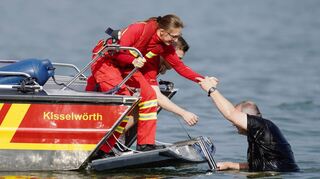 DLRG-Mitglieder demonstrieren bei einer Rettungsübung, wie sie eine Schwimmer aus dem Rhein retten.