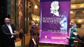 Oberbürgermeister Dr. René Pöltl (v. l.), Katharina Simmert, Nikolaus Friedrich und Rosa Grünstein präsentieren auf der Bühne des Rokokotheaters das Plakat des Mozartfests.