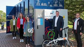 Einweihung der VRN-Radboxen, die oben mit Hockenheimer Wahrzeichen bedruckt sind: Janina Dörflinger (Firma Kienzler), Anna Hinrichs (VRN), Stefanie Simonis (Stadt), OB Marcus Zeitler und Christian Wühl (Abteilungsleiter Planung und Angebot Verkehrsverbund Rhein-Neckar) stellen die neue Fahrrad-Abstellmöglichkeit vor.