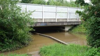 Die Unterführung der Schnellbahntrasse. Rechts der Mauer fließt normalerweise der Kriegbach, links ist Platz für Fußgänger. Der-zeit können diese die Unterführung nicht passieren – der Bach hat sich breitgemacht.