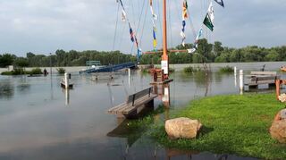 Der Flaggenmast am Ende der Rheinallee steht einsam im Wasser, die Bänke darunter sind vom Wasser umgeben, der Strom dahinter zieht schnell vorbei.