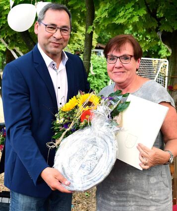Bürgermeister Jürgen Kappenstein übergibt Roselinde Zeilfelder die Geschenke.