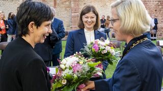 Beim Empfang im Judenhof anlässlich der Anerkennung der SchUM-Städte Speyer, Worms und Mainz überreicht OB Stefanie Seiler (r.) zusammen mit Staatssekretärin Nicole Steingaß einen Blumenstrauß an Dr. Stefanie Hahn (l.), die das Projekt begleitet hat.