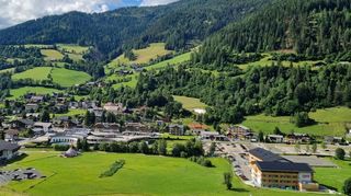 Ein wunderschönes Urlaubsparadies im österreichischen Bundesland Kärnten: Bad Kleinkirchheim. Hier der Blick von der Winter-Skipiste auf das Cooee alpin (rechts), die Römerbadtherme (mittig) und die Talstation von der Kaiserburgbahn (links) mit dem kleinen Flow Trail für Kinder. Im Hintergrund sind die Nockberge zu sehen.