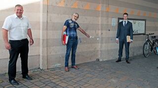 Feuchtgebiet: Am Übergang vom Zehntscheunenplatz zur Karlsruher Straße stehen Oberbürgermeister Marcus Zeitler (v. l.), Adi Graf, Rechtsanwalt Robert Mehrmann und Sachverständiger Lothar Thürer vor der Wand, die durch anstehendes Regenwasser immer wieder nass wird. Nach Grafs Überzeugung wurde das Pflaster bei der Neugestaltung des Platzes nicht sachgerecht verlegt, die Wand sei weder durch ein richtiges Gefälle noch durch eine Rinne vor Durchfeuchtung geschützt.