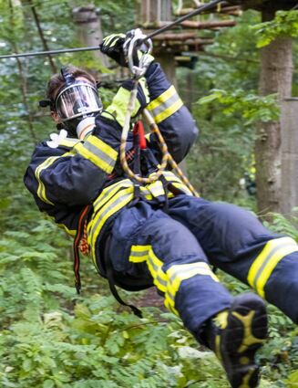 Der Gefahrstoffzug der Feuerwehr übt in voller Montur und Ausrüstung im Kletterwald den Einsatz und dabei hier die Personenrettung von Verletzten.