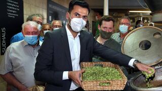 Sandhausens neuer Bürgermeister Hakan Günes (vorne) gibt den Hopfen in den Sudkessel. Welde-Chef Max Spielmann (rechts dahinter), Hopfenbauer Albert Burkhardt (l.) und die anderen Sandhäuser verfolgen die Aktion ganz stolz.