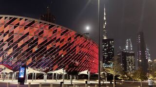 Stadt der Superlative: die Coca-Cola Arena in Dubai mit (im Hintergrund) dem höchsten Gebäude der Welt, dem Burj Khalifa – beides beschienen vom gerade über der Stadt aufgehenden Mond.