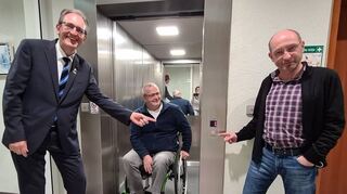 Bürgermeister Dr. Ralf Göck und Bauleiter Chris Oelsner zeigen dem Behinderten-beauftragten Rudi Bamberger den neuen und größeren Aufzug.