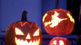 Geschnitzte Halloween-Kürbisse mit Kerzen stehen vor einem Haus.