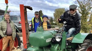 Fritz Rösch ist mit seinem „Wurstkocher“, dem Allgaier-Traktor, vorgefahren. Paul und Steffi Ehrlich (im Hintergrund) sowie ein Besucher bestaunen das herausgeputzte Vehikel mit Ährenstrauß in der Front.
