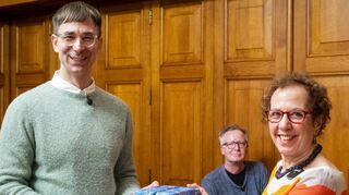 Die Stadt Speyer hat bei einer Feierstunde im Historischen Ratssaal den alle drei Jahre ausgeschriebenen Arno-Reinfrank-Literaturpreis an den Autor Tijan Sila (l.) für seinen Roman „Die Fahne der Wünsche“ übergeben. Stifterin Jeanette Koch (r.) überreicht dem Autor ein Geschenk.