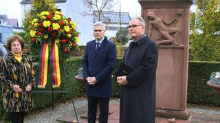 Gerda Schilling (v. l.), Bürgermeister Matthias Steffan und Diakon Bernhard Carl gedenken auf dem Friedhof.