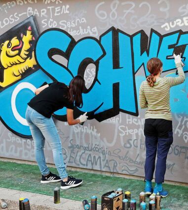Jugendliche aus Schwetzingen und der Partnerstadt Schrobenhausen gestalten ein gemeinsames Städtepartnerschaftsgraffiti an der Hilda-Turnhalle.