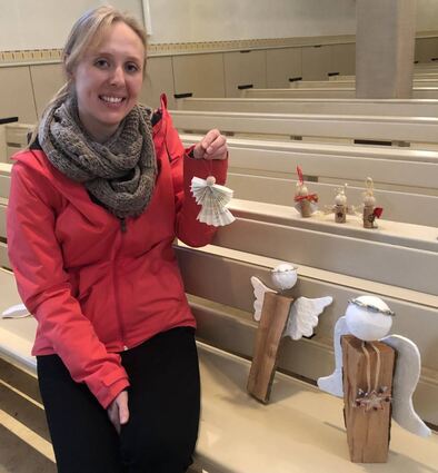 Christina Laubscher sitzt in der Kirche neben einem Teil ihrer gebastelten Engel.