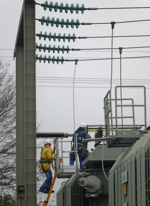 Zwei Männer arbeiten in einer Umspannanlage an den Transformatoren. Ein Brand in einer Umspannstation kann zu einem Stromausfall führen.