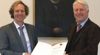 Dr. Alexander Schubert erhält die Ur-kunde von Dr. Bernhard Eitel.