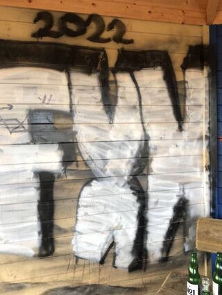 „2022 – FXK“ ist auf der Holzwand zu lesen.