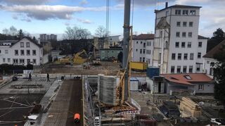 Der Blick über die Baustelle des neuen Event- und Verwaltungsgebäudes (links) Richtung Obere Langgasse. Rechts der stehen gebliebene Turm des früheren Caritas-Hauses – des sogenannten „Seppelkastens“ (rechts).